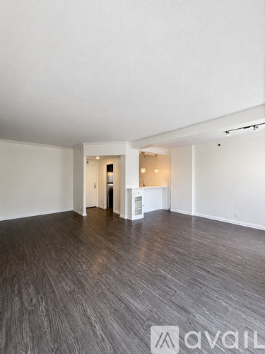 A spacious room with wooden flooring and white walls.