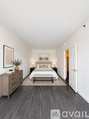 A bedroom with a bed, nightstand, and a plant on a dresser.