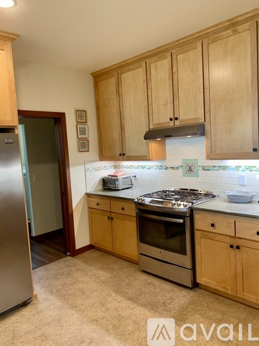 A kitchen with wooden cabinets and a stainless steel refrigerator.