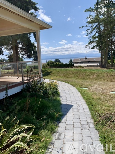 A white house with a patio and a walkway leading to a grassy area.