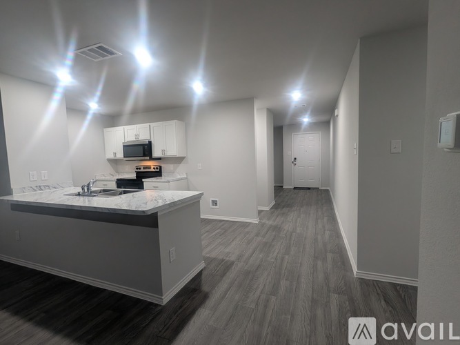 A modern kitchen with a marble countertop and wooden flooring.