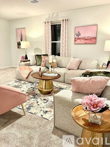 A living room with a pink couch and a gold coffee table.