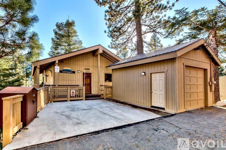 A wooden house with a garage is surrounded by trees.