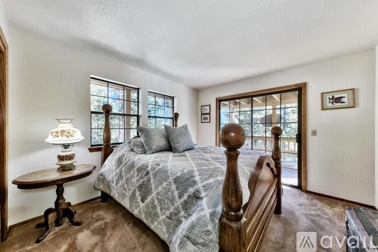 A bedroom with a bed, a table, and a window.