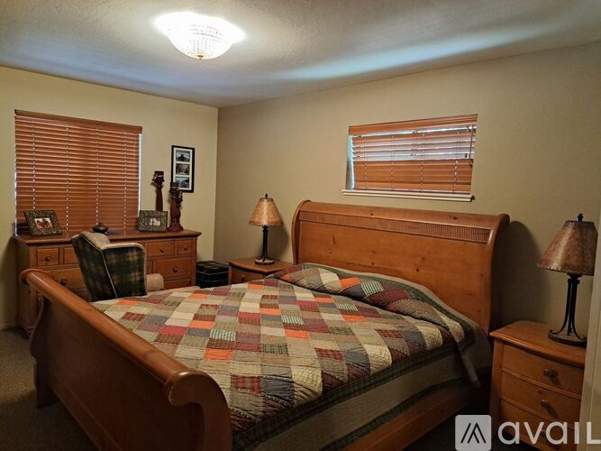 A bedroom with a bed, nightstand, and window with blinds.