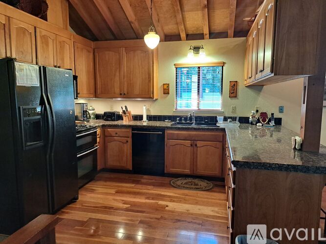 A kitchen with wooden cabinets and a black fridge.