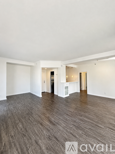 A spacious room with wooden flooring and white walls.