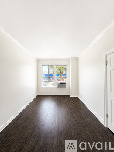 A room with wooden floors and a window overlooking a balcony.