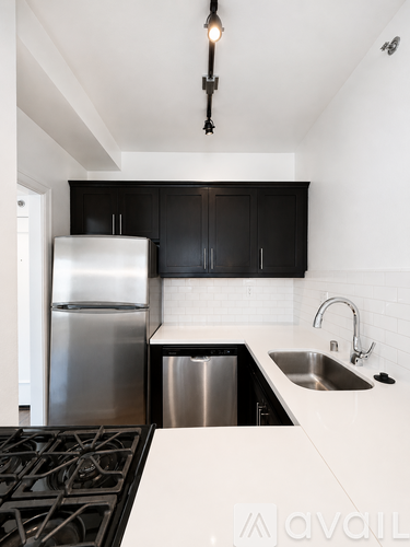 A modern kitchen with black cabinets and stainless steel appliances.