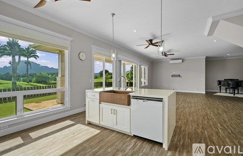 A kitchen with white cabinets and a large window overlooking a green landscape.