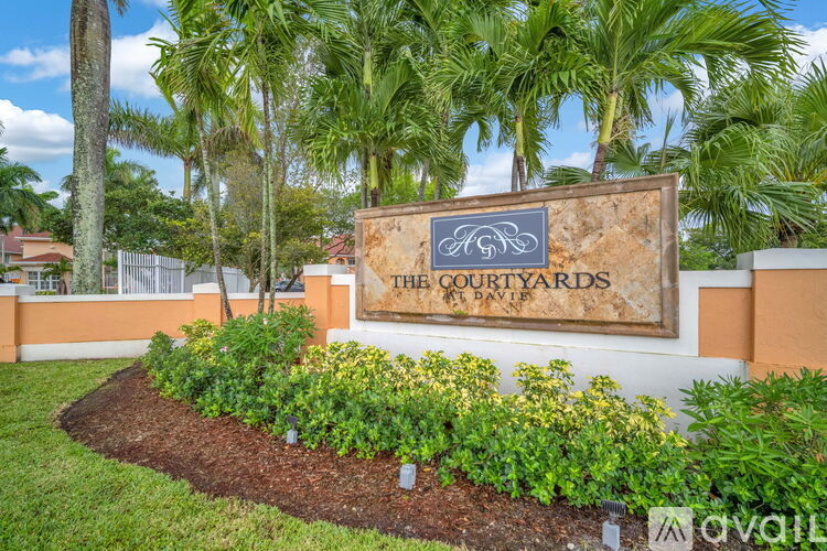 A sign that says "The Courtyards" is in front of some trees.