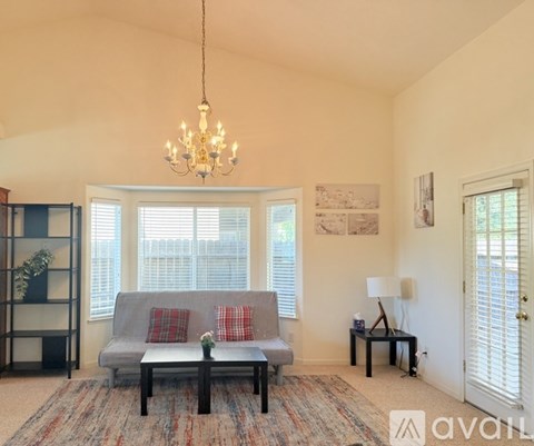 A living room with a grey couch and a chandelier.