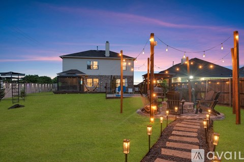 A house with a lawn and a pathway with lights leading to a gazebo.
