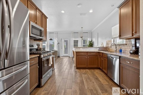 A kitchen with wooden cabinets and stainless steel appliances is available for rent.