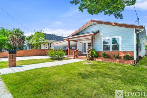 A blue house with a brown roof and a white fence.