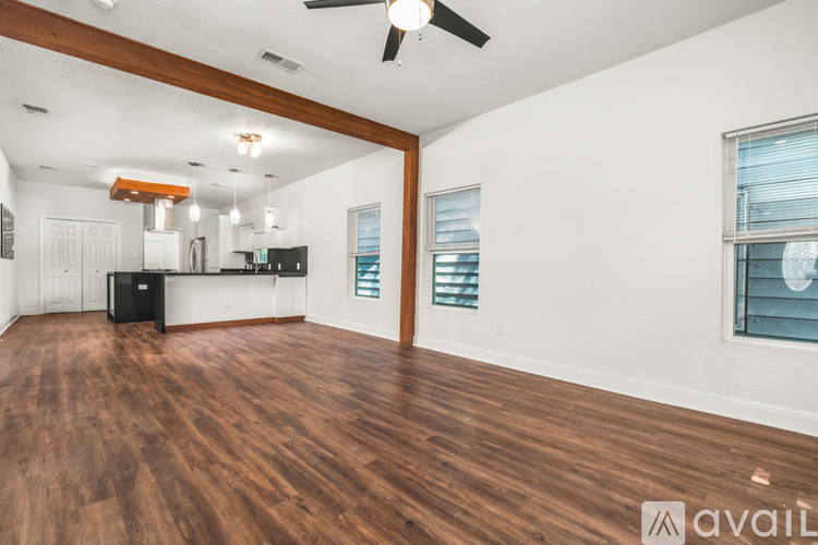 A spacious room with wooden floors and a ceiling fan.