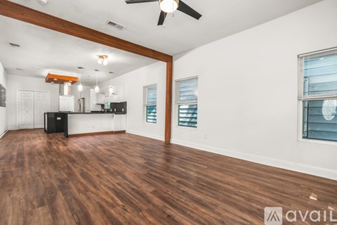 A spacious room with wooden floors and a ceiling fan.
