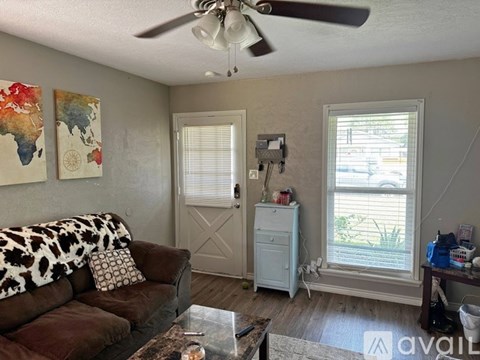 A living room with a brown couch and a ceiling fan.