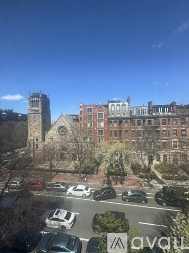 A view of a parking lot with cars and a building with a clock tower in the background.