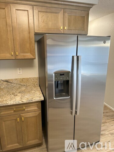 A kitchen with a stainless steel refrigerator and wooden cabinets.