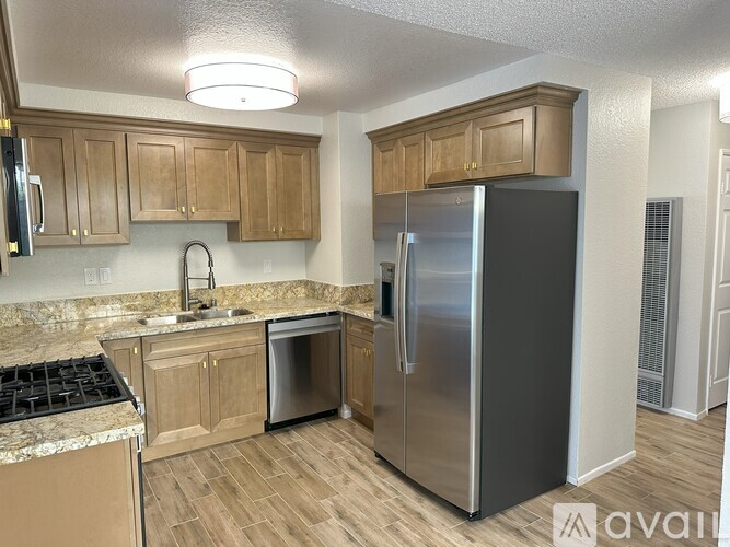 A kitchen with wooden cabinets and a stainless steel refrigerator.