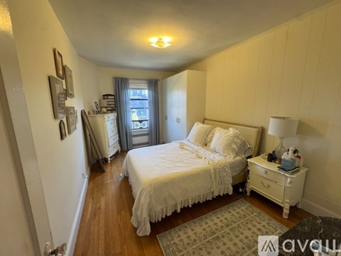 A bedroom with a large bed and a window with curtains.