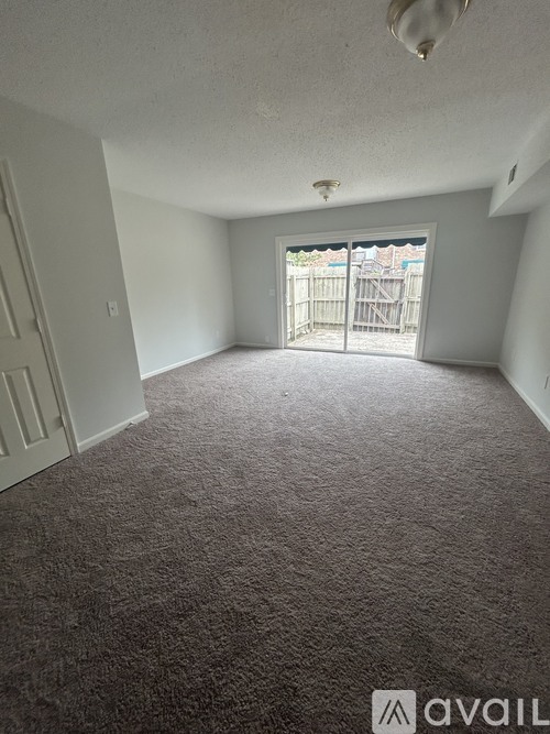A carpeted room with a sliding glass door leading to a deck.