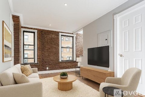 A living room with a couch, chair, and television.