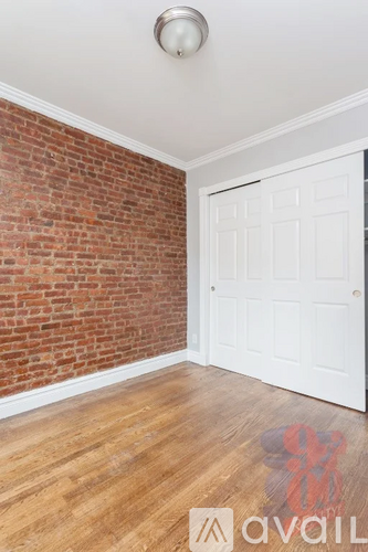 A room with a white door and a brick wall.