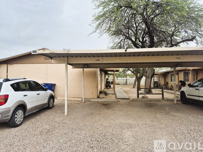 A carport with two cars parked in front of a house.