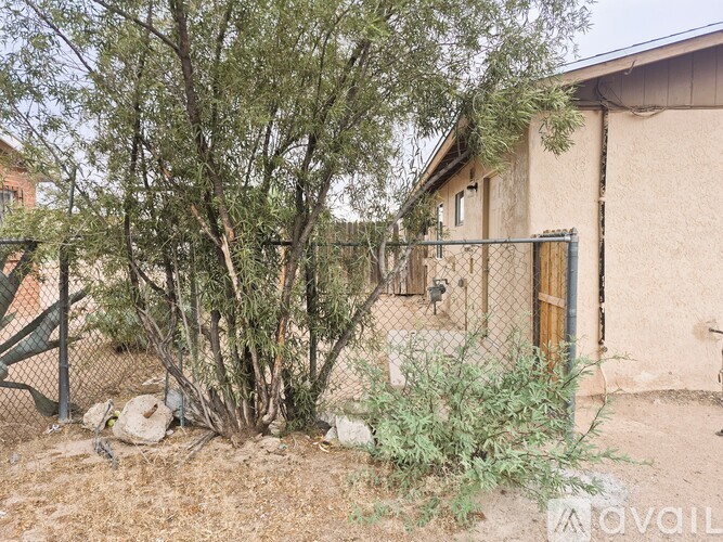 A house with a fence and trees in front.