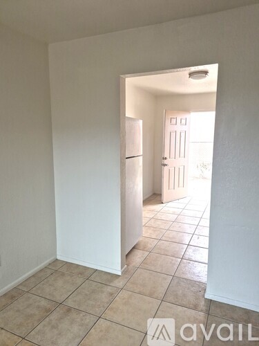 A kitchen area with a white fridge and tiled floor.