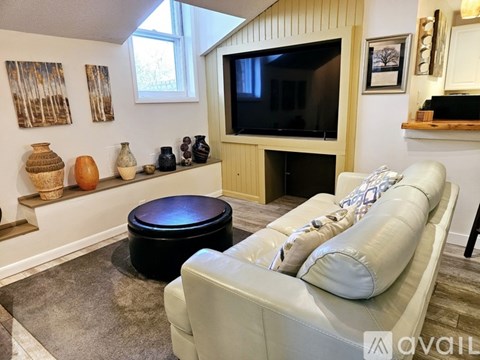 A living room with a grey couch and a black ottoman.