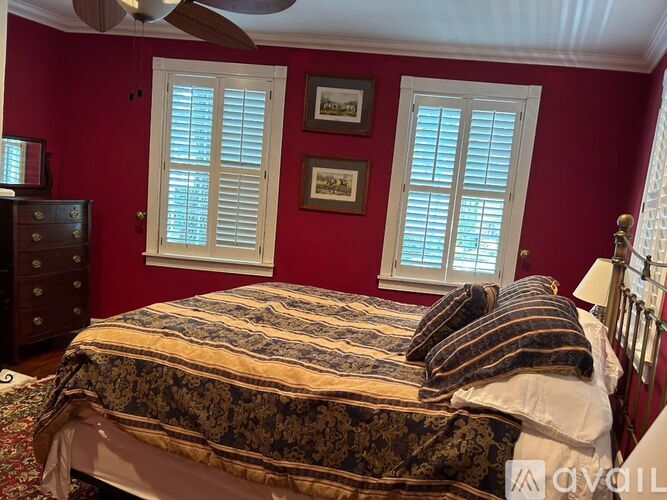 A bedroom with red walls and a bed with a patterned comforter.