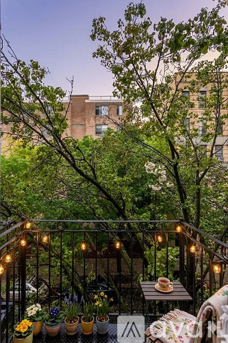 A balcony with a table, chairs, and potted plants.