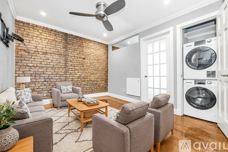 A living room with a brick wall and a washer and dryer in the background.