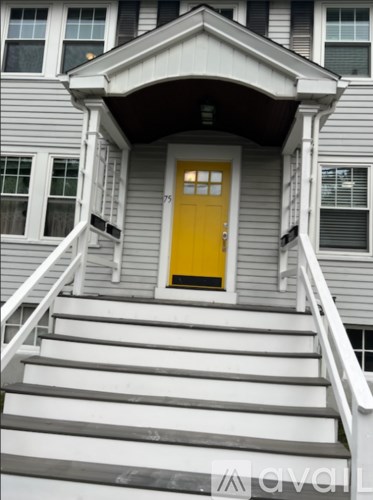 A grey house with a yellow door and white stairs.