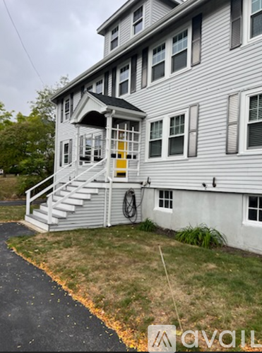 A grey house with a yellow door and a white staircase.