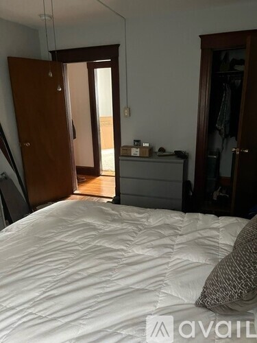 A bedroom with a large bed and a wooden wardrobe.