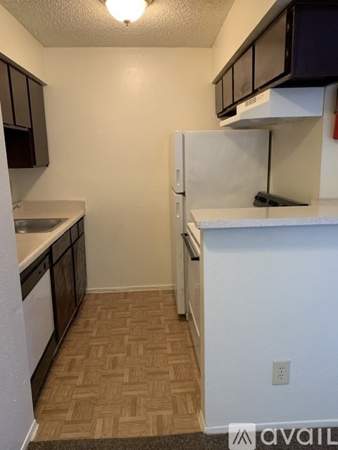 A kitchen with a white refrigerator and brown cabinets.