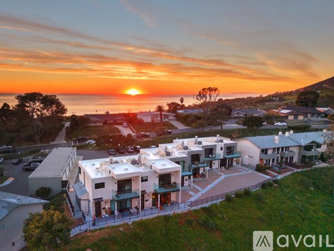 A sunset view of a residential area with houses and a street.