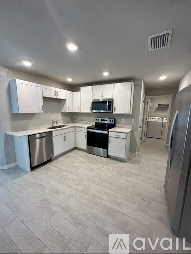 A kitchen with white cabinets and a stainless steel refrigerator.