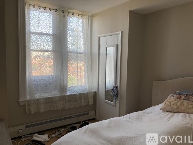 A bedroom with a bed, window with curtains, and a door.