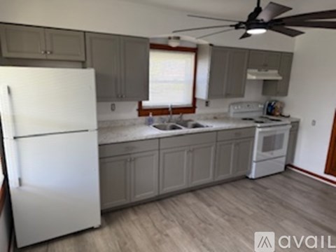 A kitchen with a white refrigerator and wooden floors.