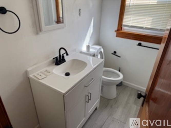 A bathroom with a sink, toilet, and a window.