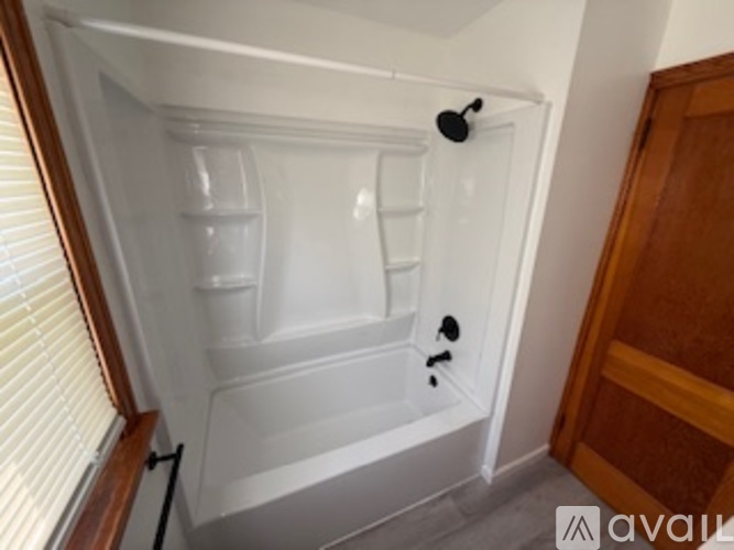 A small white bathroom with a shower stall and a wooden door.