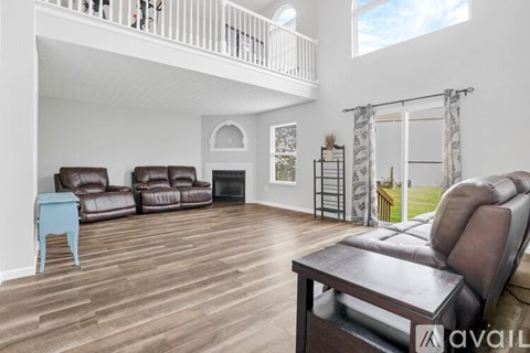 A living room with brown leather furniture and a balcony.