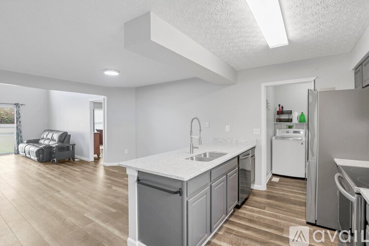 A kitchen with a white countertop and wooden flooring.
