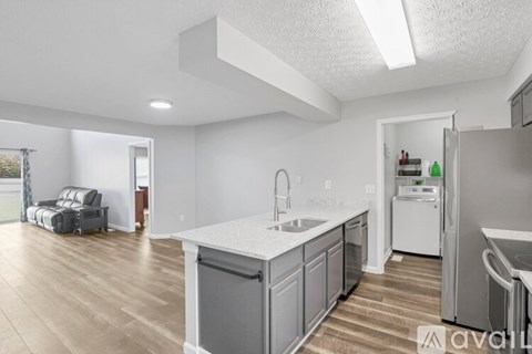 A kitchen with a white countertop and wooden flooring.