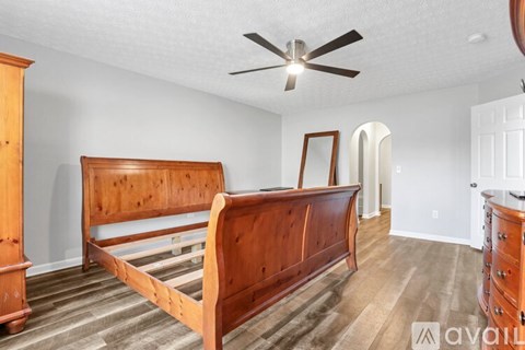 A bedroom with a large bed and a ceiling fan.
